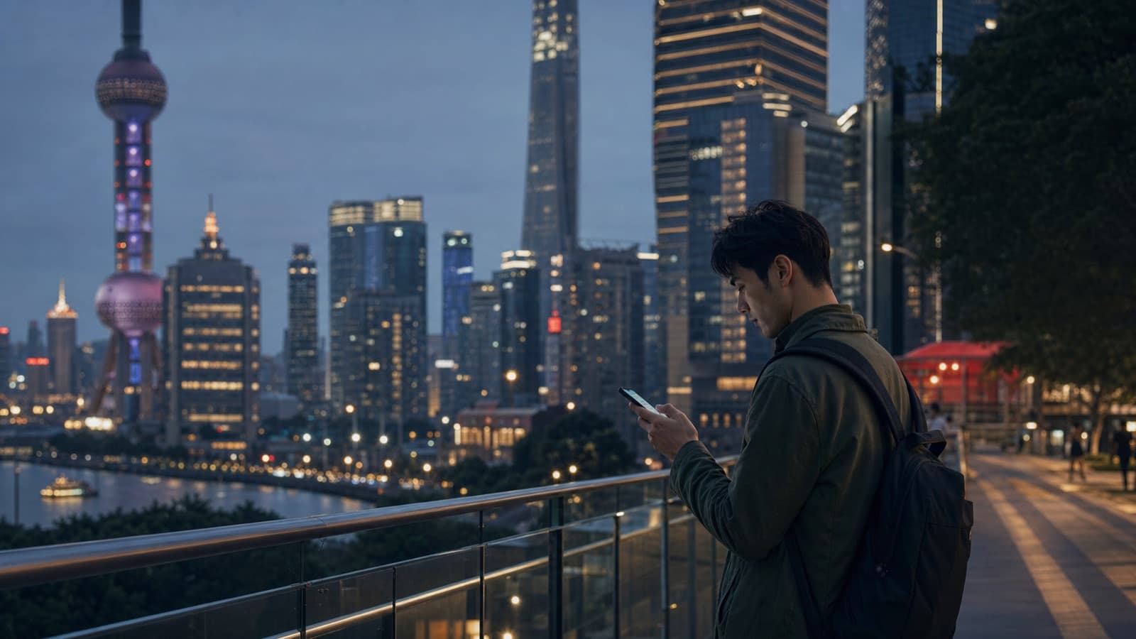 Traveler using a smartphone on a modern Shanghai riverside terrace at dusk.